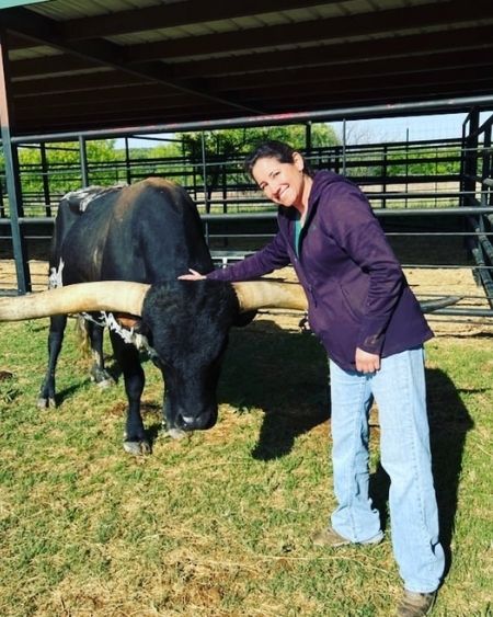 Texas West Animal Health Staff petting a cow with large horns
