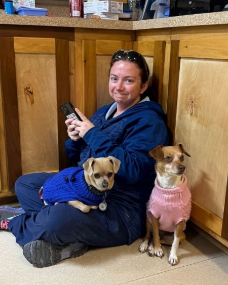 Texas West Animal Health Staff sitting on the floor with two dogs in sweaters